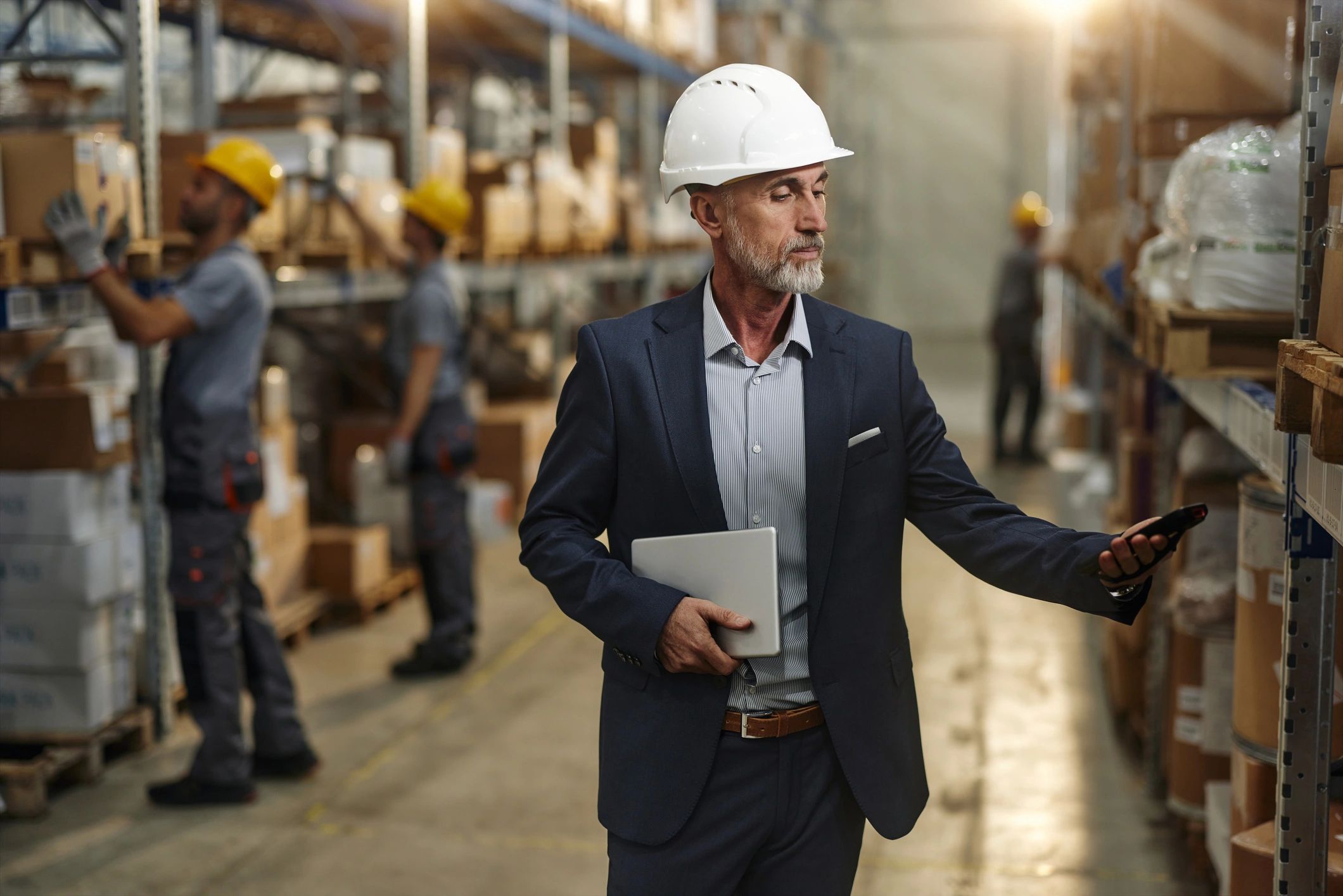 Senior male inspector using bar code reader to scan a package in a warehouse.