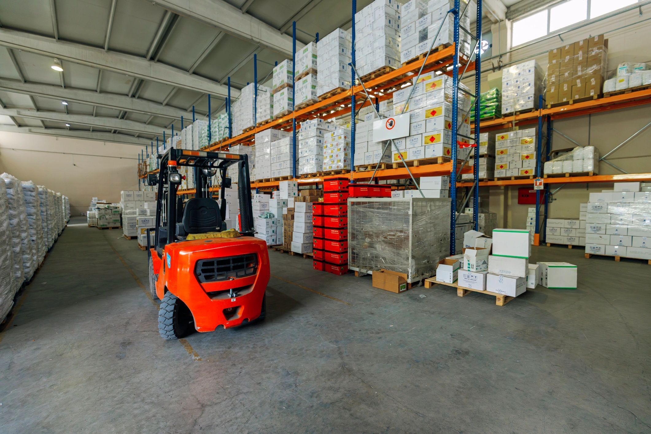 Industrial Forklift in Spacious Warehouse Aisle with Stacked Goods and Pallets